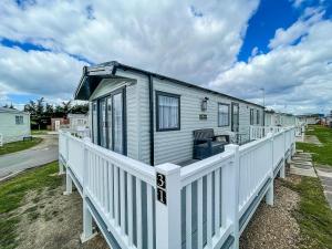 a tiny house with a white railing on a deck at Stunning 6 Berth Caravan At Suffolk Sands Holiday Park Ref 45031g in Felixstowe