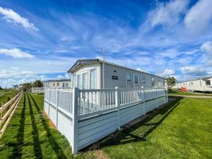 una casa blanca con una valla en un campo de hierba en Beautiful 6 Berth Caravan With Full Sea Views For Hire In Suffolk Ref 68002cr en Lowestoft