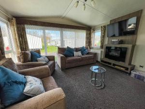 a living room with couches and a flat screen tv at Beautiful Caravan With Decking At California Cliffs In Scratby Ref 50052l in Great Yarmouth