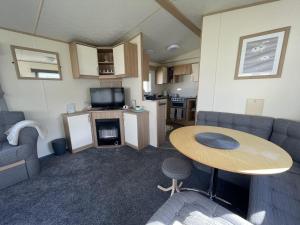 a living room with a table and a kitchen at Great 8 Berth Caravan At Highfield Grange, Clacton-on-sea Ref 26214o in Clacton-on-Sea