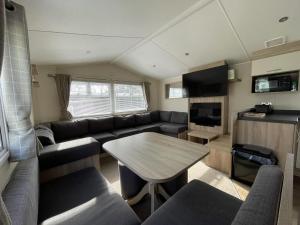 a living room with a couch and a table at Wonderful 8 Berth Caravan With Wi-fi And Decking At Seawick, Ref 27023sw in Clacton-on-Sea