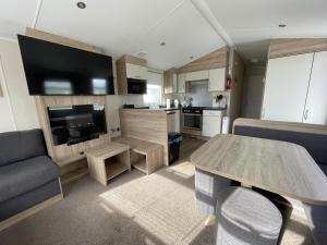 a living room with a table and a kitchen at Wonderful 8 Berth Caravan With Wi-fi And Decking At Seawick, Ref 27023sw in Clacton-on-Sea