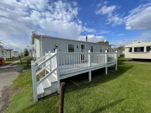 a mobile home with a white porch and a fence at Wonderful 8 Berth Caravan With Wi-fi And Decking At Seawick, Ref 27023sw in Clacton-on-Sea