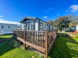 a tiny house with a wooden deck in a yard at Beautiful Caravan For Hire With A Partial Sea View In Suffolk Ref 32042az in Lowestoft