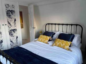 1 dormitorio con 1 cama con almohadas azules y amarillas en SNUGGLES en Weymouth
