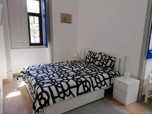 um quarto com uma cama com um edredão preto e branco em A CASA DA VILA em Almodôvar