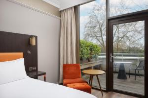 ロンドンにあるダブルツリー バイ ヒルトン ロンドン ハイドパークのベッドとバルコニー付きのホテルルーム