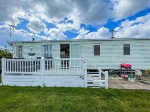 a white house with a porch and a yard at Brilliant Caravan With Decking And Wifi At Dovercourt Park In Essex Ref 44010a in Great Oakley