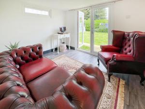 een woonkamer met een leren bank en 2 stoelen bij Spring Lodge in Southbourne