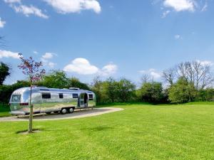 a trailer parked in a field next to a tree at Lanes End Farm Airstream in Hawthorn