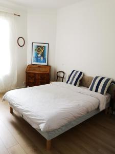 ein Bett mit blauen und weißen gestreiften Kissen darauf in der Unterkunft COROLLE Whole flat with garden near Paris in Vitry-sur-Seine