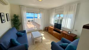 a living room with a blue couch and a television at Residencial Marina de Port in L'Ametlla de Mar