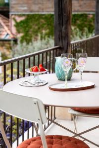 a white table with two glasses and a plate of fruit at La petite madeleine - Chambre d'hôtes & spa in Burgy