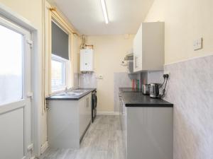 a small kitchen with white cabinets and a sink at Lovely large 2-Bed House with 2 Reception Rooms in Atherstone