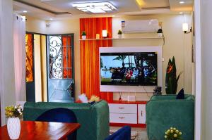a living room with a flat screen tv and green chairs at Le meublé des voyageurs in Yaoundé