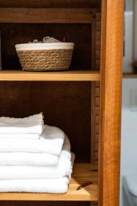 une pile de serviettes sur une étagère avec un panier dans l'établissement La petite madeleine - Chambre d'hôtes & spa, à Burgy