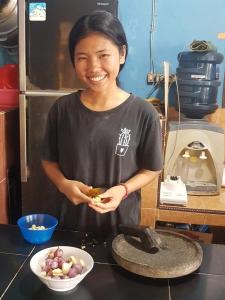 a woman standing in a kitchen with a bowl of food at Harus Damai Inn in Lagudri
