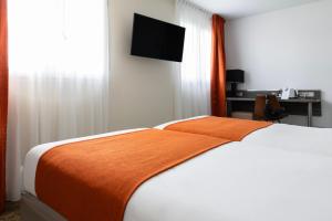 a bedroom with a bed with an orange blanket on it at Hôtel Atrium in Arles