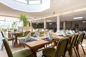 une salle à manger avec des tables en bois et des chaises vertes dans l'établissement Hôtel Atrium, à Arles