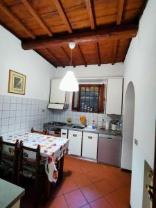 CASA DI NAT في Pratolino: مطبخ مع طاولة ومطبخ مع دواليب بيضاء