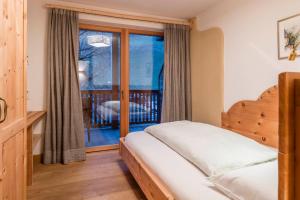 a bedroom with a bed and a window with a balcony at Alma Apartments in Luson