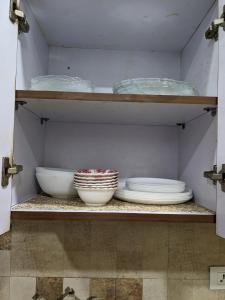 a shelf with plates and bowls in a cabinet at Excellent Home Away from Home! in Noida