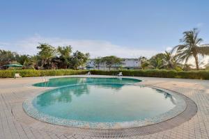 a large pool in a courtyard with chairs and trees at Goverdhan Greens Resort Dwarka l Hotels In Dwarka in Dwarka