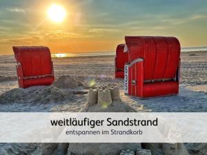 two red beach chairs sitting on the beach at strandnahe Familien-Oase mit Kinderbuggy in Bensersiel