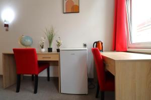 a kitchen with a desk and a refrigerator and red chairs at Golden’s Apart-Hotel in Vienna