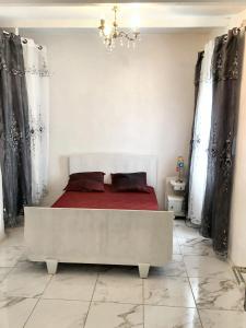 1 dormitorio con 1 cama blanca con sábanas y cortinas rojas en Maison d'une chambre avec jardin clos et wifi a Avignon, en Aviñón