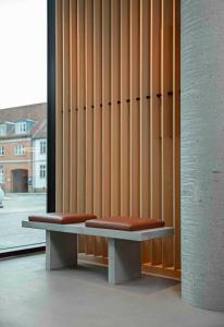 dwie ławki siedzące przed drewnianą ścianą w obiekcie Zleep Hotel Hillerød w mieście Hillerød