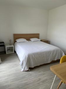 a bedroom with a white bed and a wooden table at Cosy 2 pièces et parking 30 mns Gare du Nord by immokitbnb in Villepinte