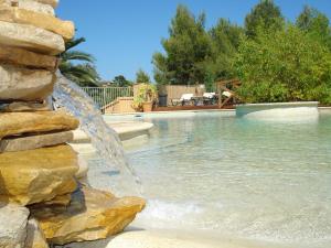 a pool with a water fountain in a yard at Les Cyprès in La Cadiere d'Azur