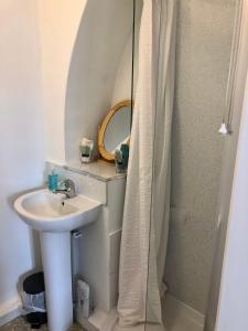 uma casa de banho com um lavatório e um chuveiro com um espelho. em Knoll Guest House em Cromer