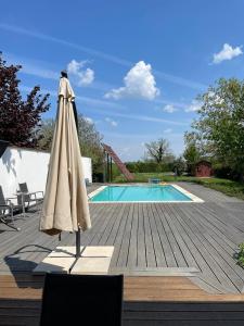 una sombrilla sentada en una terraza junto a una piscina en Freistehendes Ferienhaus mit Swimmingpool, Kamin, Internet, unweit Neusiedlersee, en Fertőd
