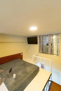 1 dormitorio con 1 cama y TV en la pared en 34 LOFT Duplo · LOFT 900m São Paulo Expo/ 300mts metrô Jabaquara, en São Paulo