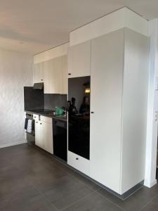 kuchnia z białymi szafkami i czarnym urządzeniem w obiekcie LakeHill72 w mieście Seelisberg