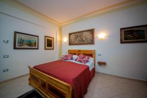a bedroom with a bed with red sheets and pictures on the wall at Hotel "SAN SAENA " in Vlorë