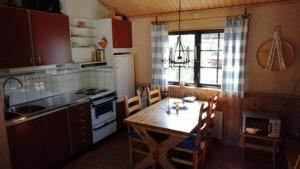 une cuisine avec une table en bois, une table et des chaises dans l'établissement Kleines Ferienhaus auf Naturgrundstück in Seenähe - b48624, à Sollerön