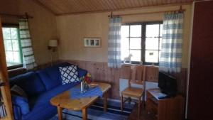 a living room with a blue couch and a table at Kleines Ferienhaus auf Naturgrundstück in Seenähe - b48624 in Sollerön