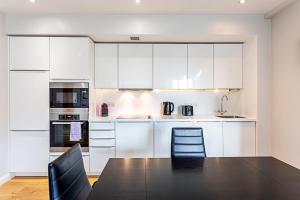 a kitchen with white cabinets and a table and chairs at Wonderful Holborn Apartment in London