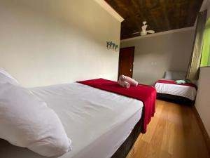 a bedroom with two beds with a red blanket at Pousada Vista Serra PRADOS MG in Prados