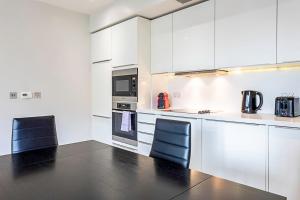 eine Küche mit weißen Schränken sowie einem Tisch und Stühlen in der Unterkunft Wonderful Holborn Apartment in London