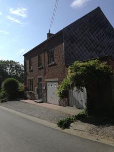 uma casa de tijolos vermelhos com uma garagem branca em Au fil des champs em Berzée