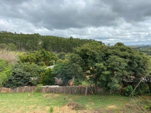 un gran árbol en un campo con una valla en Pousada Vista Serra PRADOS MG, en Prados