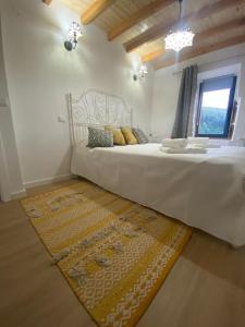 um quarto com uma grande cama branca e um tapete em Casinha Pôr do Sol em Aldeia das Dez