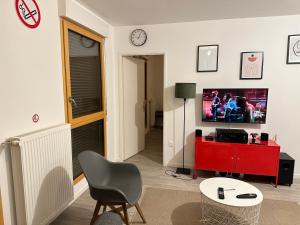 a living room with a television and a red dresser at Cosy 2 pièces et parking 30 mns Gare du Nord by immokitbnb in Villepinte