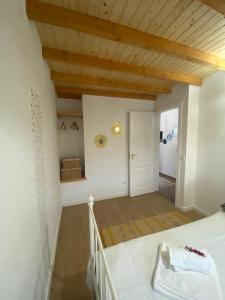 1 dormitorio con paredes blancas y techo de madera en Casinha Pôr do Sol, en Aldeia das Dez