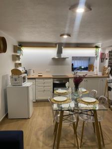 cocina con mesa de cristal con sillas y microondas en Casinha Pôr do Sol, en Aldeia das Dez