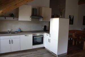 uma cozinha com armários brancos e um lavatório em Waldzeit Lodge - Ferienwohnung Eule em NeuhÃ¼tten